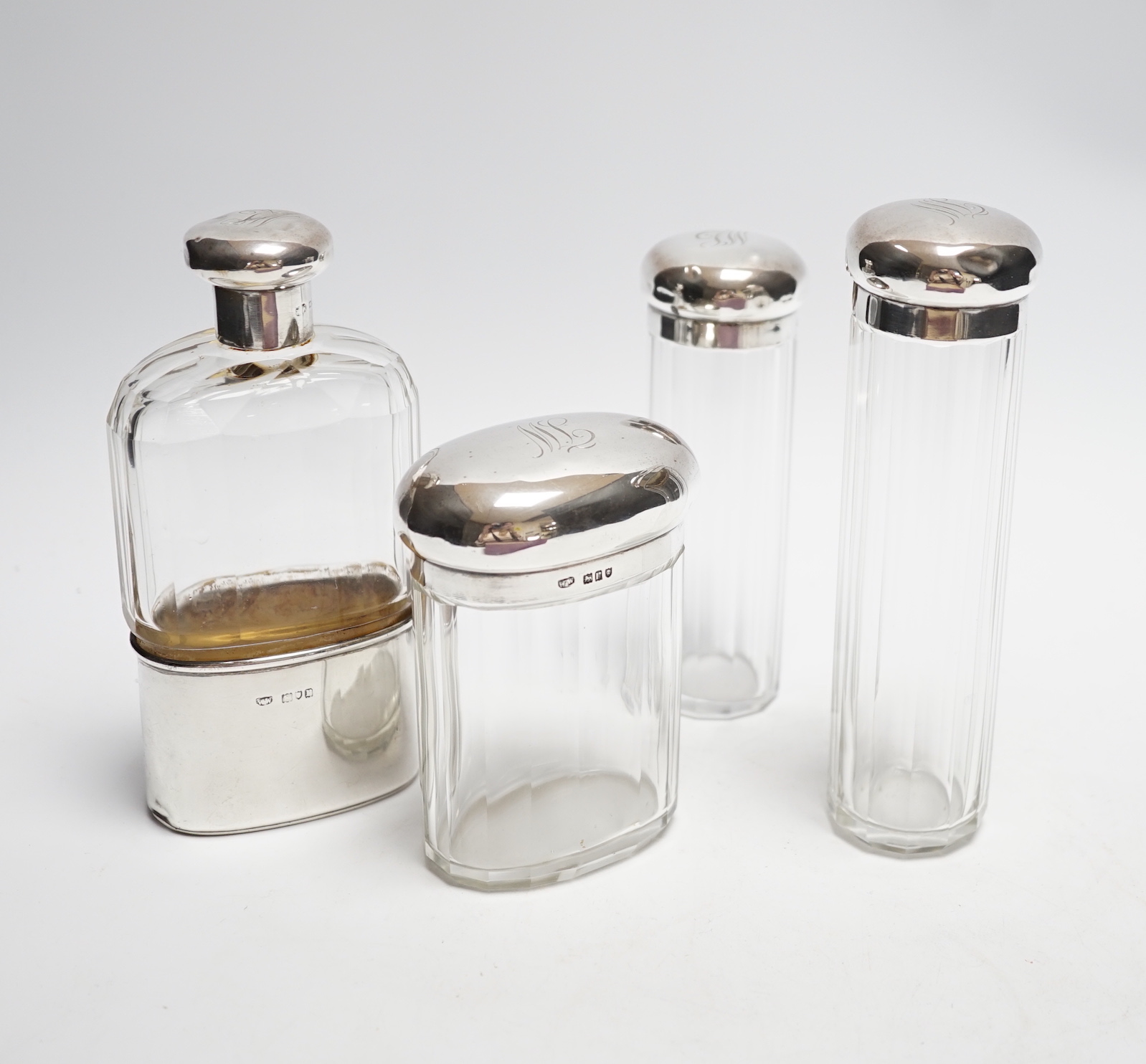 A George V silver mounted glass hip flask, London, 1912, 15.2cm, together with three matching silver mounted glass toilet jars.